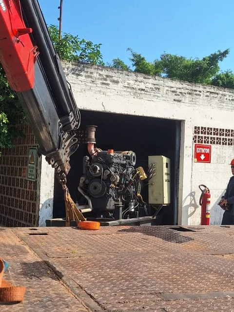 Vista frontal del generador RESA 450 KVA siendo elevado con brazo hidráulico de camión grúa
