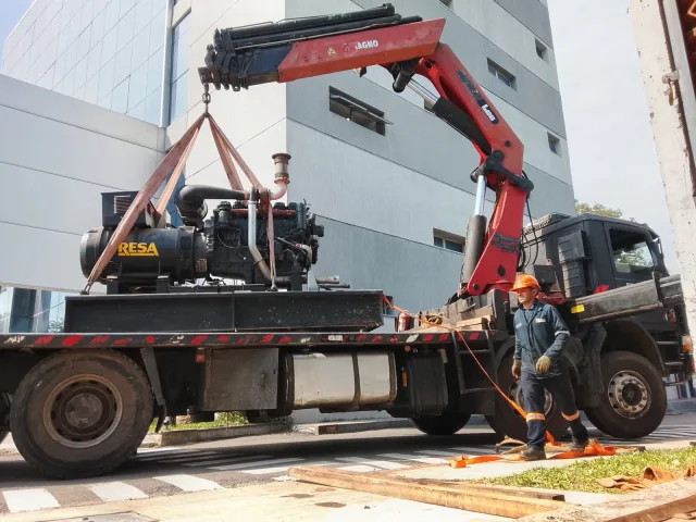 Generador RESA 450 KVA asegurado con correas para traslado en plataforma de camión grúa