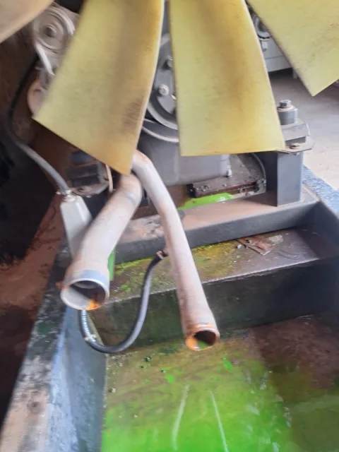 Detalle de tubos metálicos del radiador con signos de corrosión y residuos de refrigerante en zona inferior.