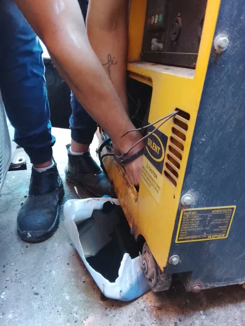 Técnico realizando trabajo de mantenimiento en interior del generador Kipor inspeccionando sus componentes internos.